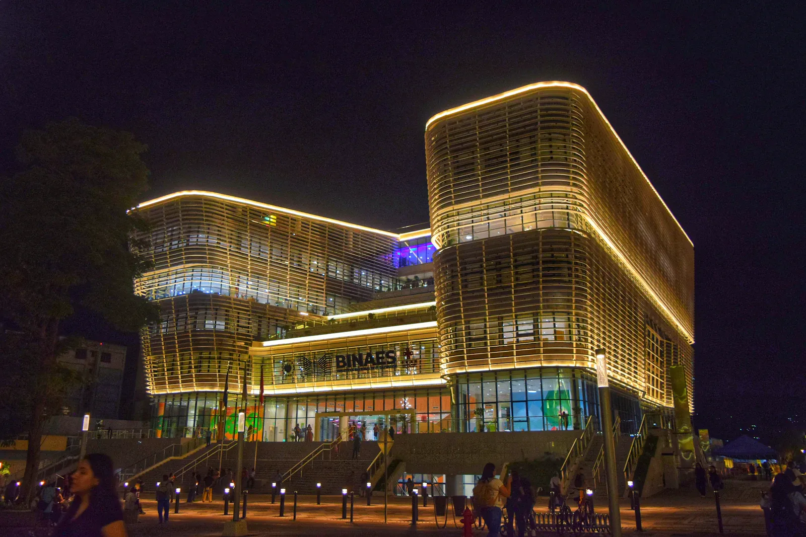 Personas afuera de un edificio iluminado de noche en El Salvador
